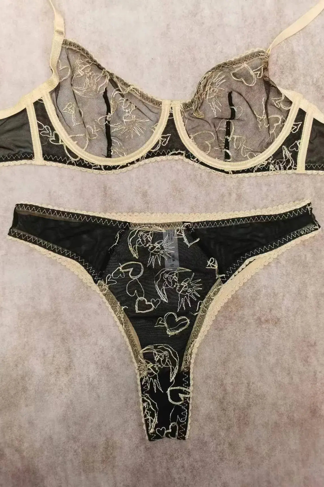 Flat lay of Black Sun & Moon Lace bra with intricate gold embroidery and lace trim.