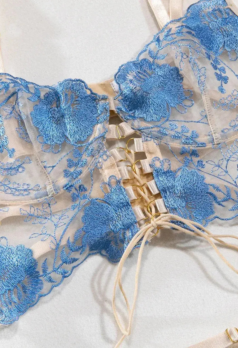 Front view of blue strappy lingerie bra with intricate floral embroidery and sheer mesh panels