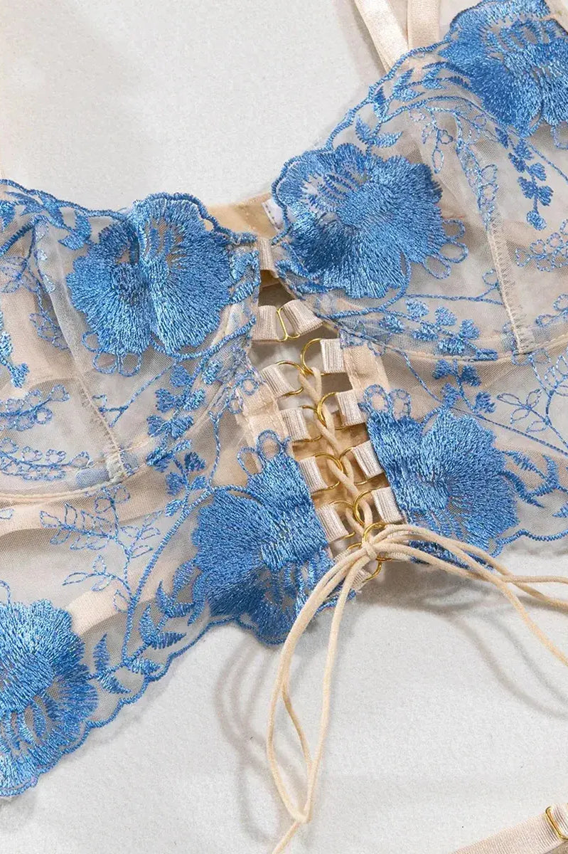 Front view of blue strappy lingerie bra with intricate floral embroidery and sheer mesh panels