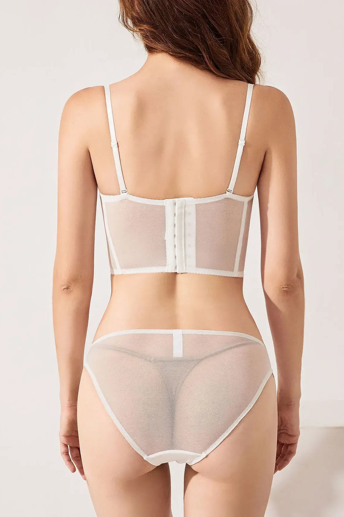 Back view of ivory lace corset top lingerie set featuring gold embroidery and sheer mesh, styled for both innerwear and outerwear.