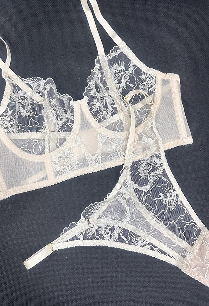 Flat lay of Ivory Whisper embroidered lingerie set showing lace fabric placement and visual balance of corset and thong.