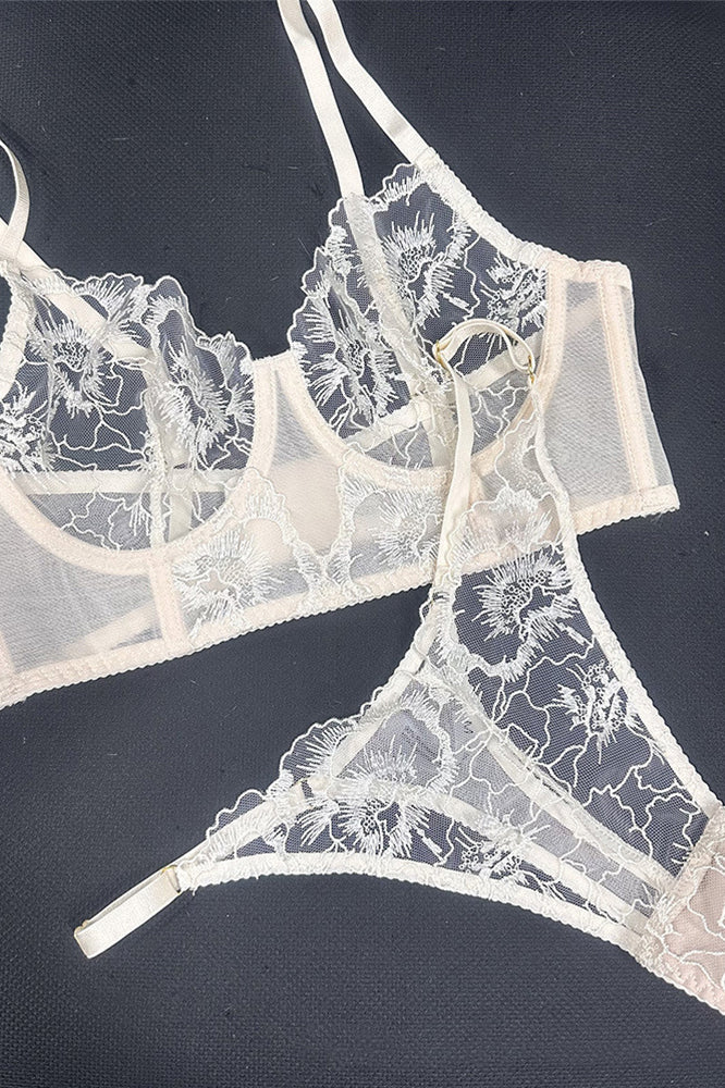Flat lay of Ivory Whisper embroidered lingerie set showing lace fabric placement and visual balance of corset and thong.