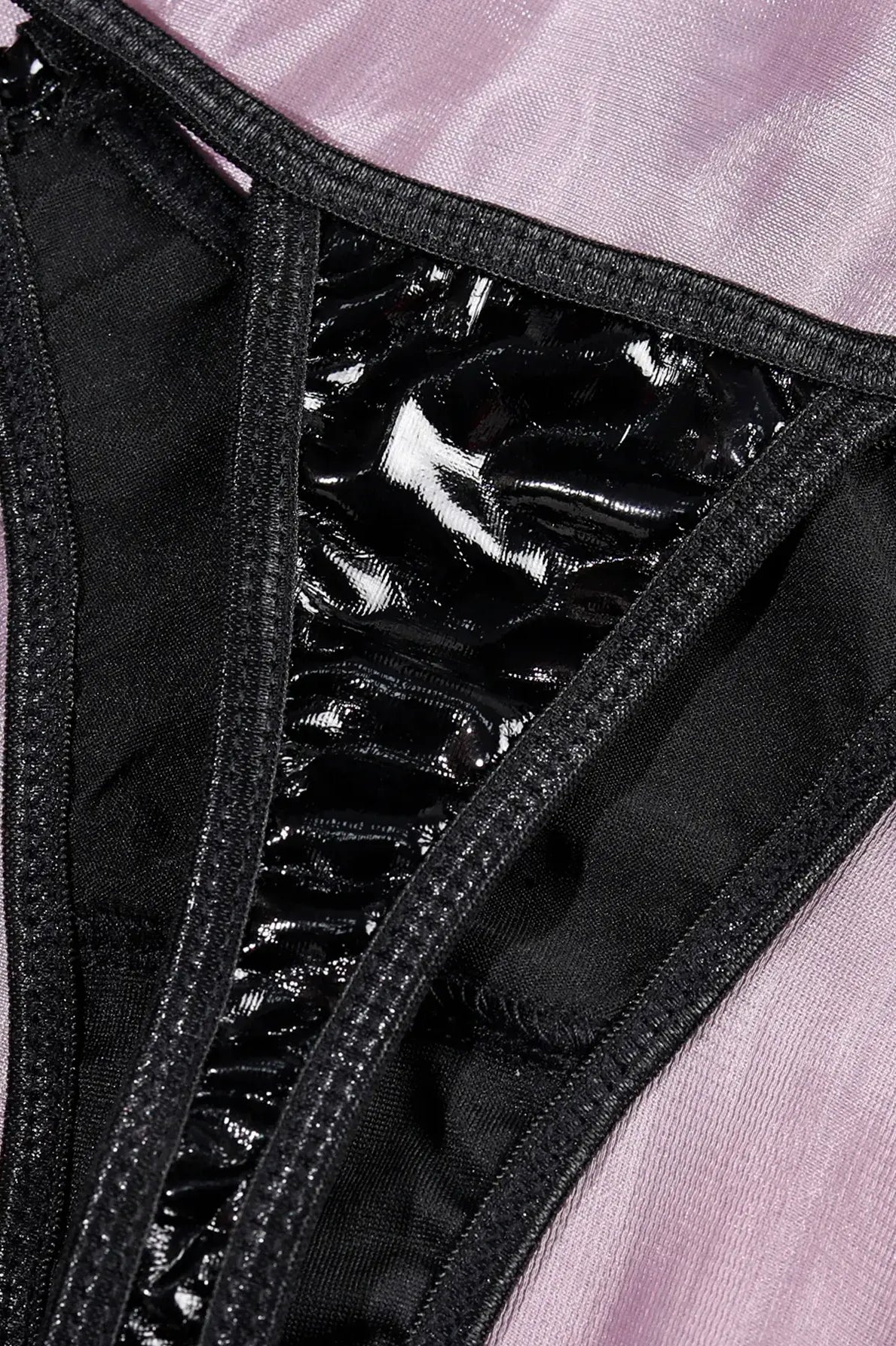 Detail of high-quality metal hardware and bondage-style connectors on the black PU leather bodysuit.