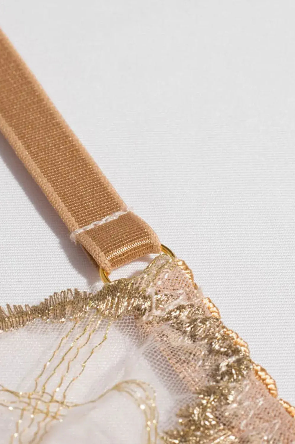 Close-up of gold embroidery thread on nude lingerie showing refined craftsmanship.