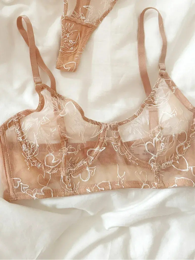 Detailed close-up of black gold lace bra showcasing fine celestial embroidery and nude mesh layering.