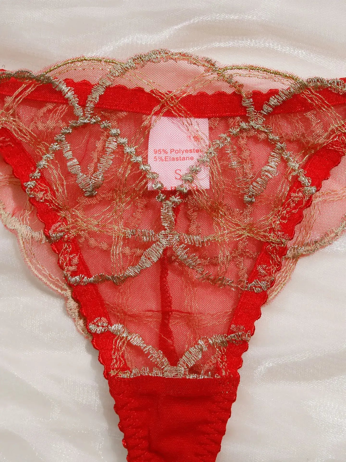 Close-up of scarlet bra with gold thread embroidery and mesh detail.