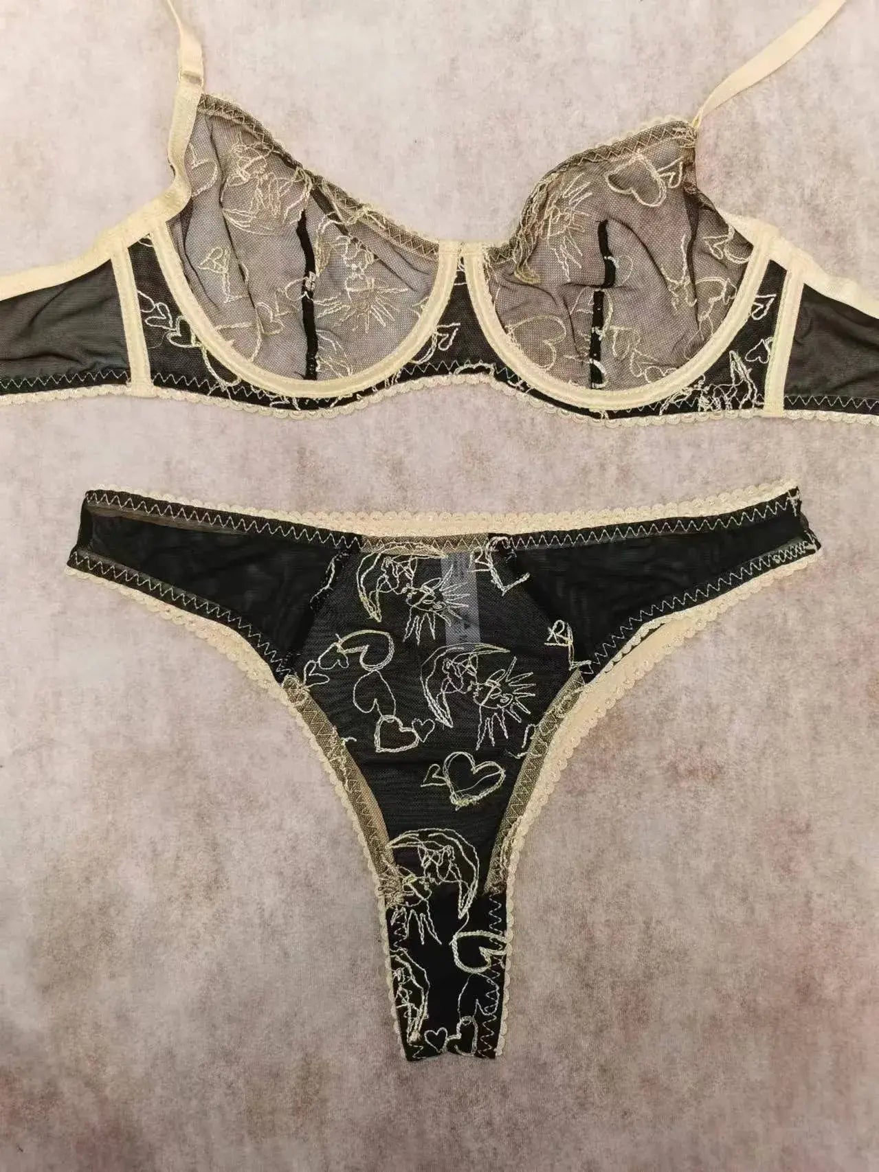 Flat lay of Black Sun & Moon Lace bra with intricate gold embroidery and lace trim.