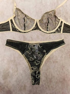 Flat lay of Black Sun & Moon Lace bra with intricate gold embroidery and lace trim.