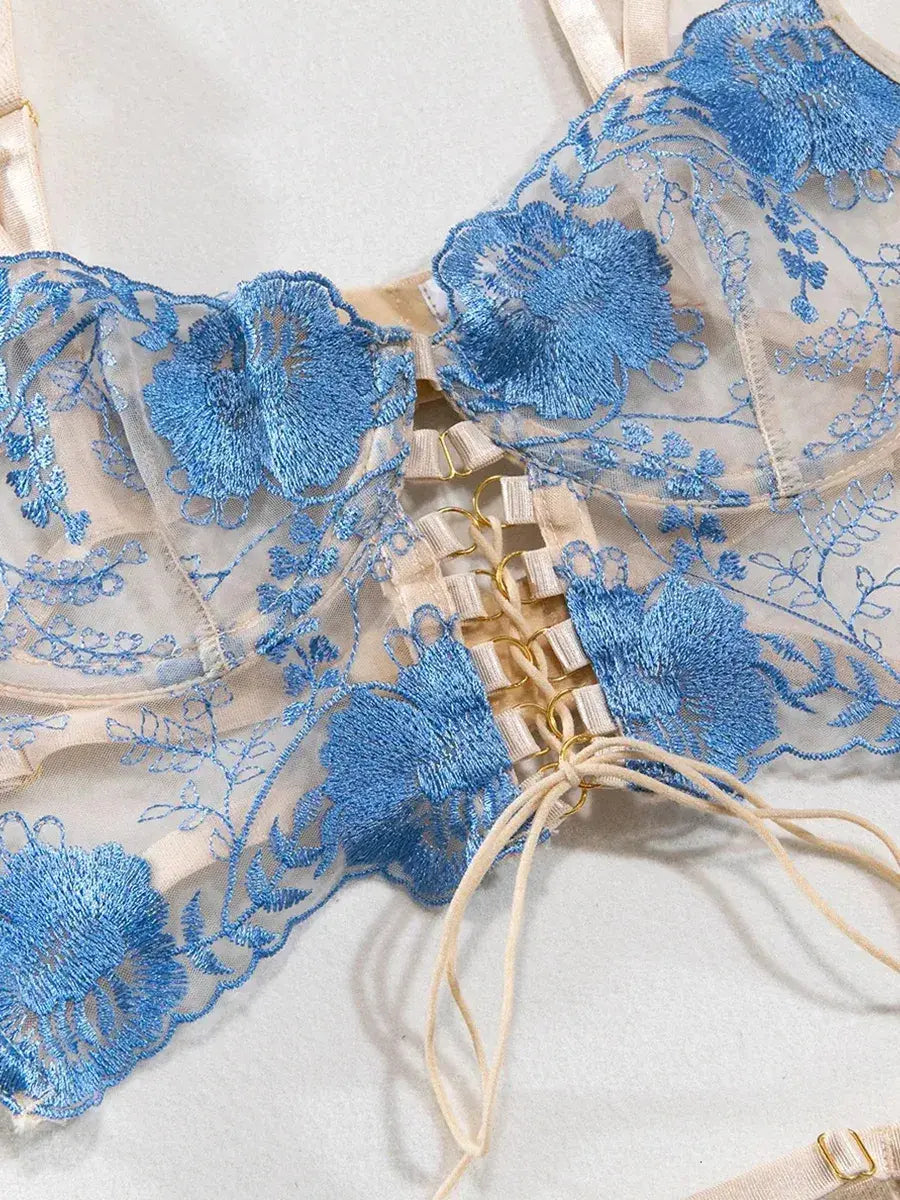Front view of blue strappy lingerie bra with intricate floral embroidery and sheer mesh panels