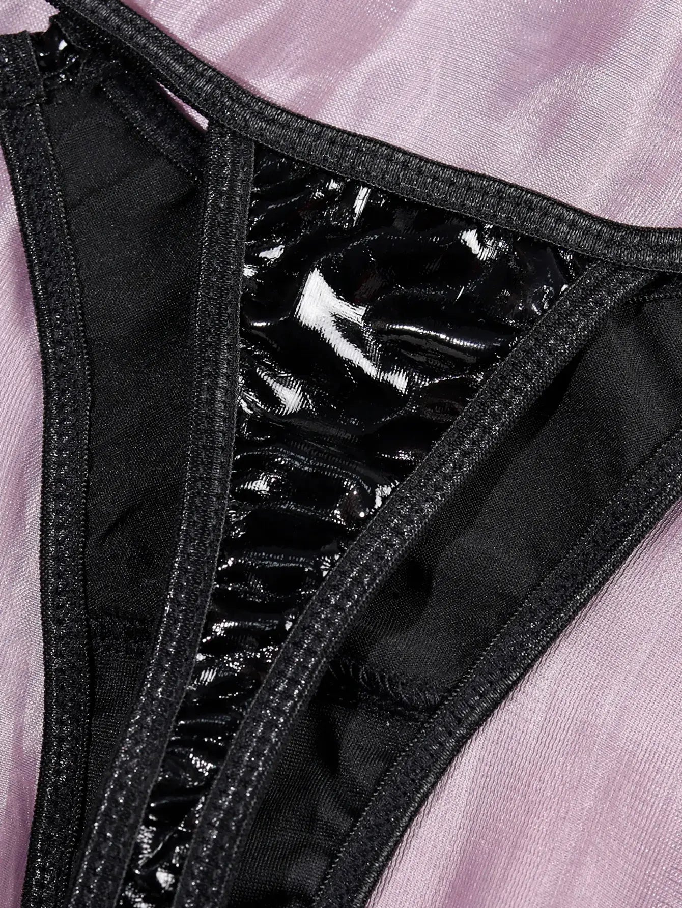 Detail of high-quality metal hardware and bondage-style connectors on the black PU leather bodysuit.