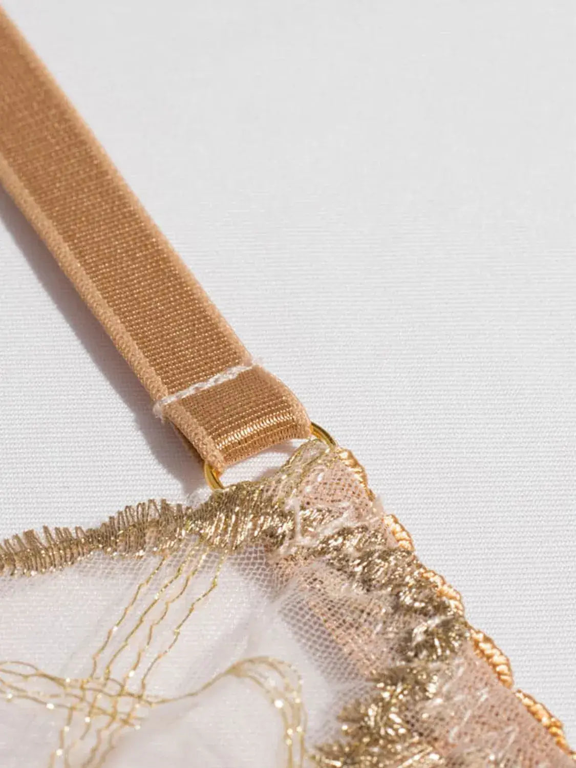 Close-up of gold embroidery thread on nude lingerie showing refined craftsmanship.