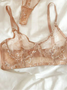 Detailed close-up of black gold lace bra showcasing fine celestial embroidery and nude mesh layering.